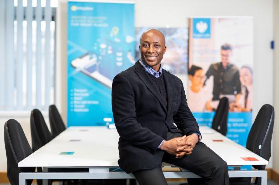 Fredi Nonyelu seated on a conference table in the Briteyellow office with company banners behind him