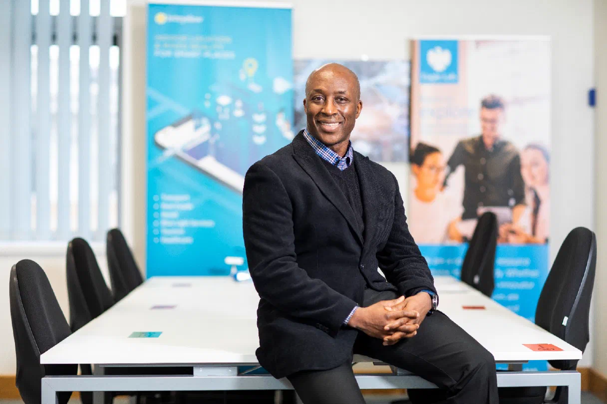 Fredi Nonyelu seated on a conference table in the Briteyellow office with company banners behind him